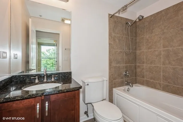 a bathroom with a granite countertop sink a mirror a bathtub and a toilet