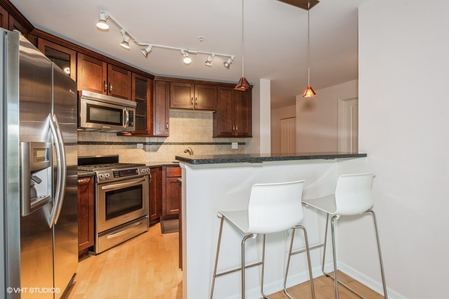 1228 Emerson Street, Unit 304 Evanston, IL 60201 - Photo 4 of 19 a kitchen with stainless steel appliances granite countertop a stove a sink and a microwave