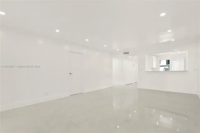 an empty room with white walls and kitchen view