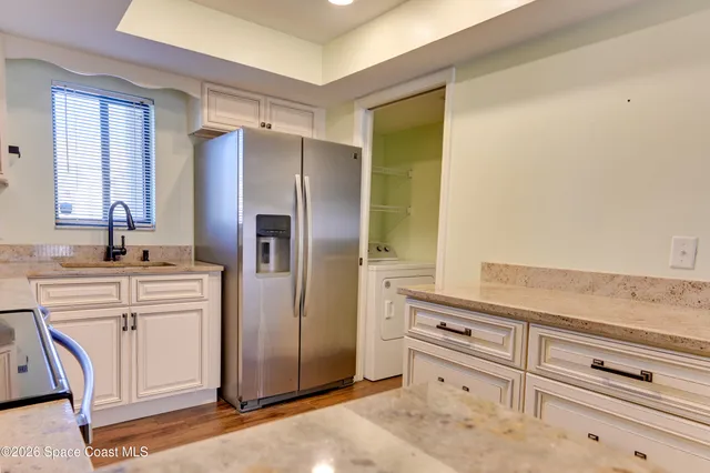 a kitchen with white cabinets and refrigerator