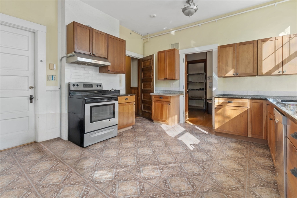 5 Claremont Street Worcester, MA 01610 - Photo 18 of 42 a kitchen with stainless steel appliances granite countertop a stove top oven a sink and a refrigerator