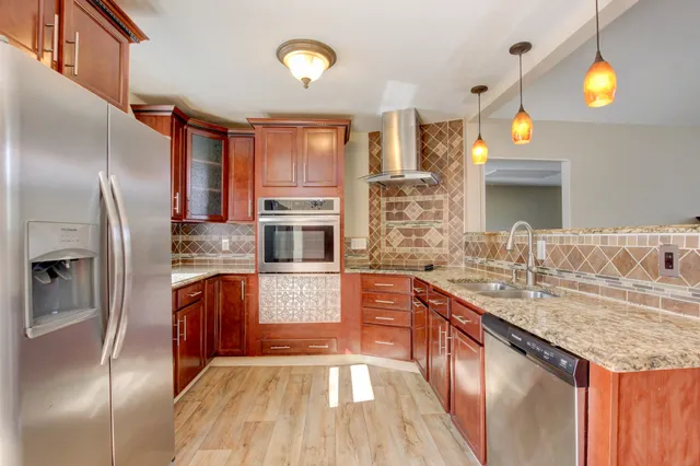 a kitchen with stainless steel appliances granite countertop a sink a stove and a refrigerator