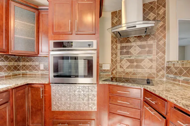 a kitchen with granite countertop wooden cabinets and a stove top oven