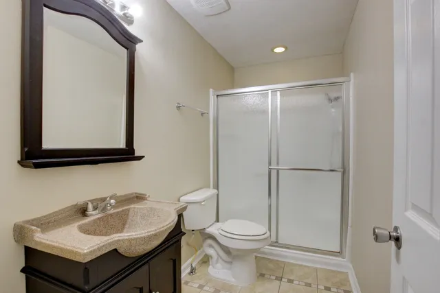 a bathroom with a toilet sink vanity and mirror