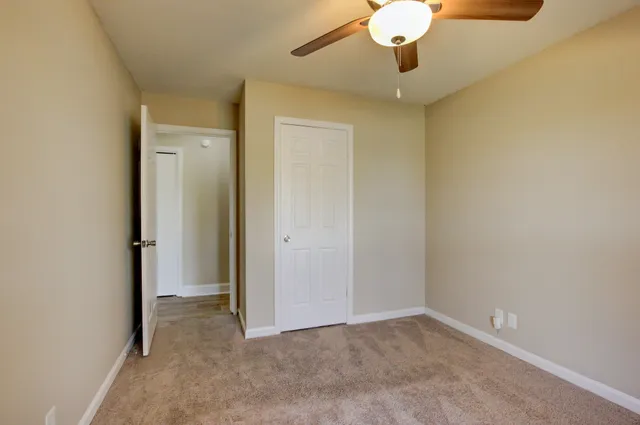 an empty room with a chandelier fan and wooden floor