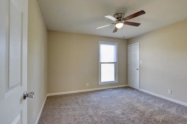 an empty room with window and ceiling fan