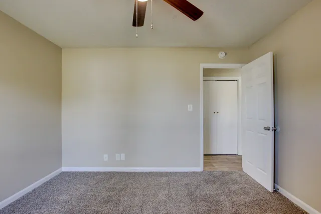 an empty room with closet and chandelier fan