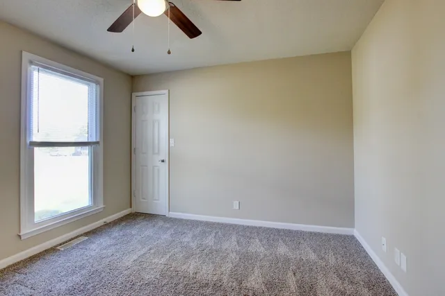 an empty room with a window and a ceiling fan