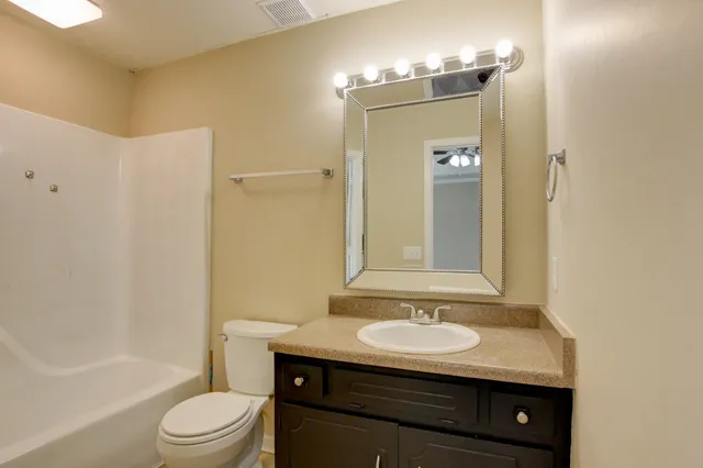 a bathroom with a granite countertop sink a toilet and shower