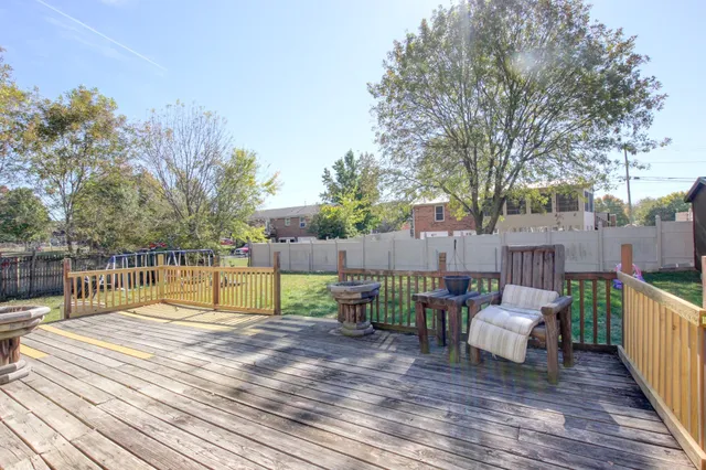 a view of house with deck outdoor seating and trees in the background