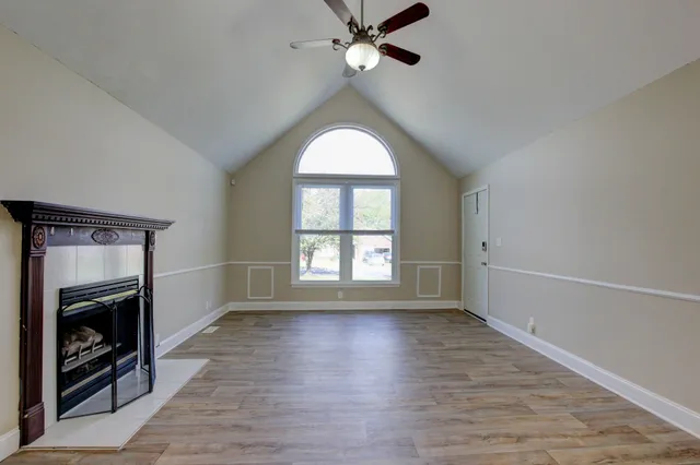 an empty room with wooden floor fan and windows