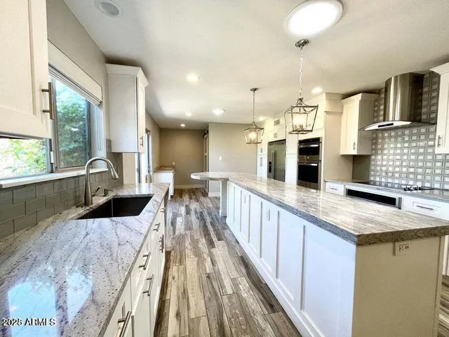 a large kitchen with stainless steel appliances kitchen island a large counter top and a wooden floors