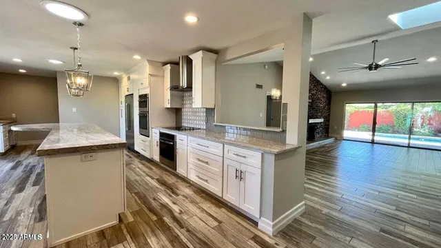 a large kitchen with stainless steel appliances kitchen island a large counter top and a wooden floors