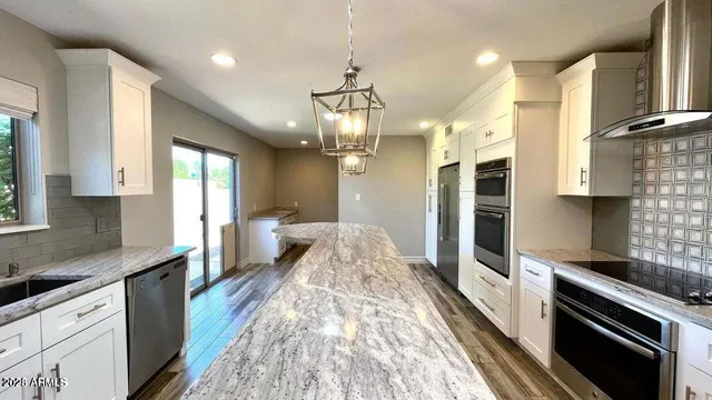 a large kitchen with granite countertop lots of counter space and stainless steel appliances