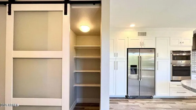 a view of a kitchen with refrigerator and wooden floor