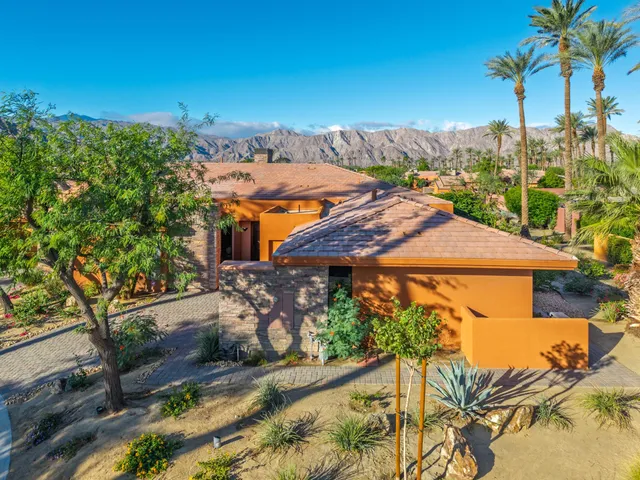 a view of a white house with a yard and potted plants