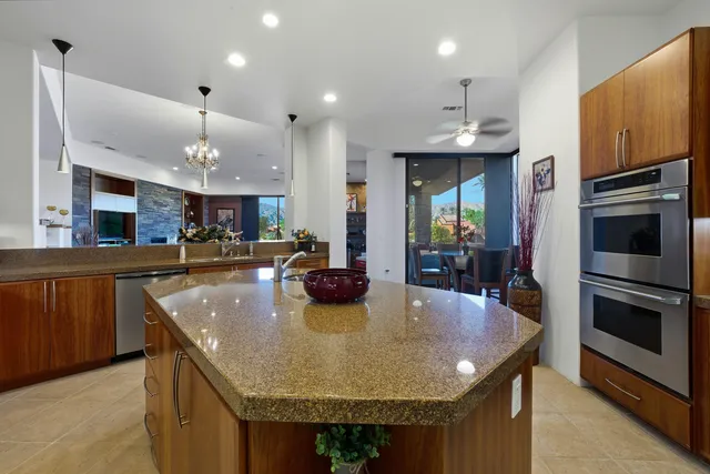 a kitchen with stainless steel appliances granite countertop a kitchen island a stove a oven a sink a counter space and cabinets