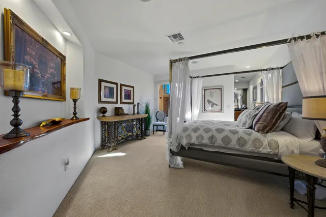 a spacious bedroom with a bed a table and painting on the wall