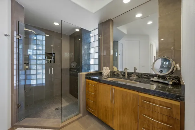 a bathroom with a granite countertop sink a mirror and shower
