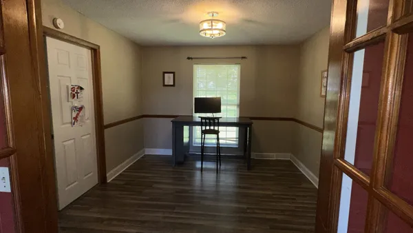 a view of a hallway with wooden floor and a living room