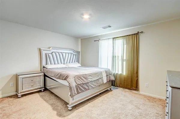 a bed sitting in a spacious bedroom next to a window