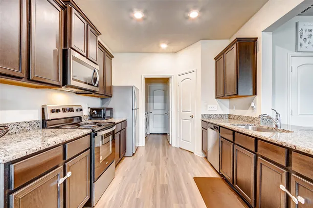 a kitchen with stainless steel appliances granite countertop wooden cabinets a stove top oven a sink and dishwasher