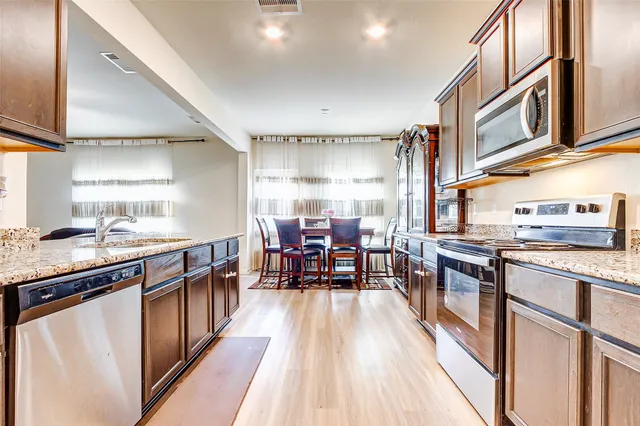 a kitchen with stainless steel appliances granite countertop sink stove top oven and cabinets