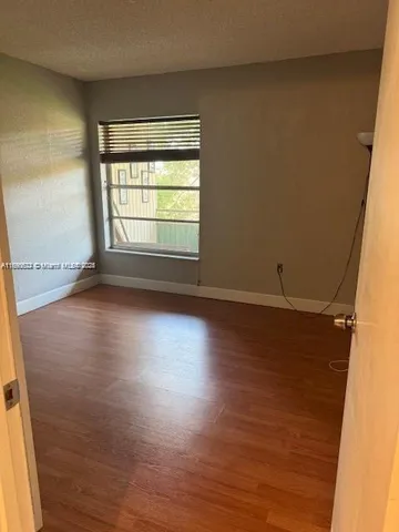an empty room with wooden floor and windows with curtains
