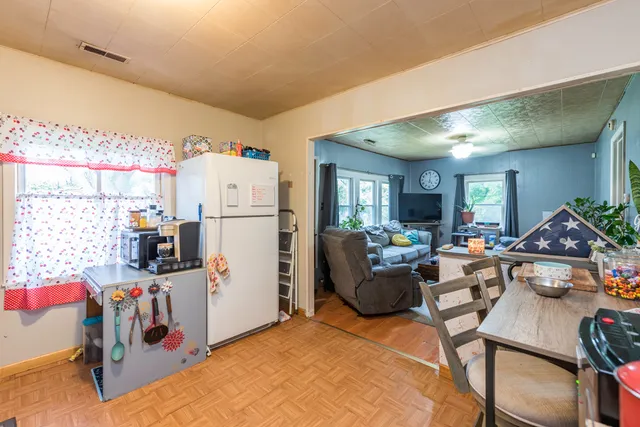 a living room with furniture a flat screen tv and a refrigerator