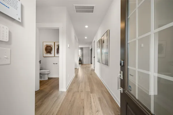 a view of a hallway with wooden floor and a bathroom