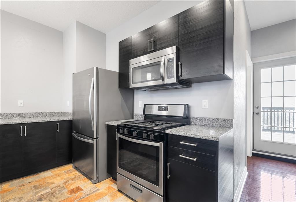 2918 Spring Street Pittsburgh, PA 15210 - Photo 7 of 25 a kitchen with stainless steel appliances granite countertop a stove a microwave and a refrigerator