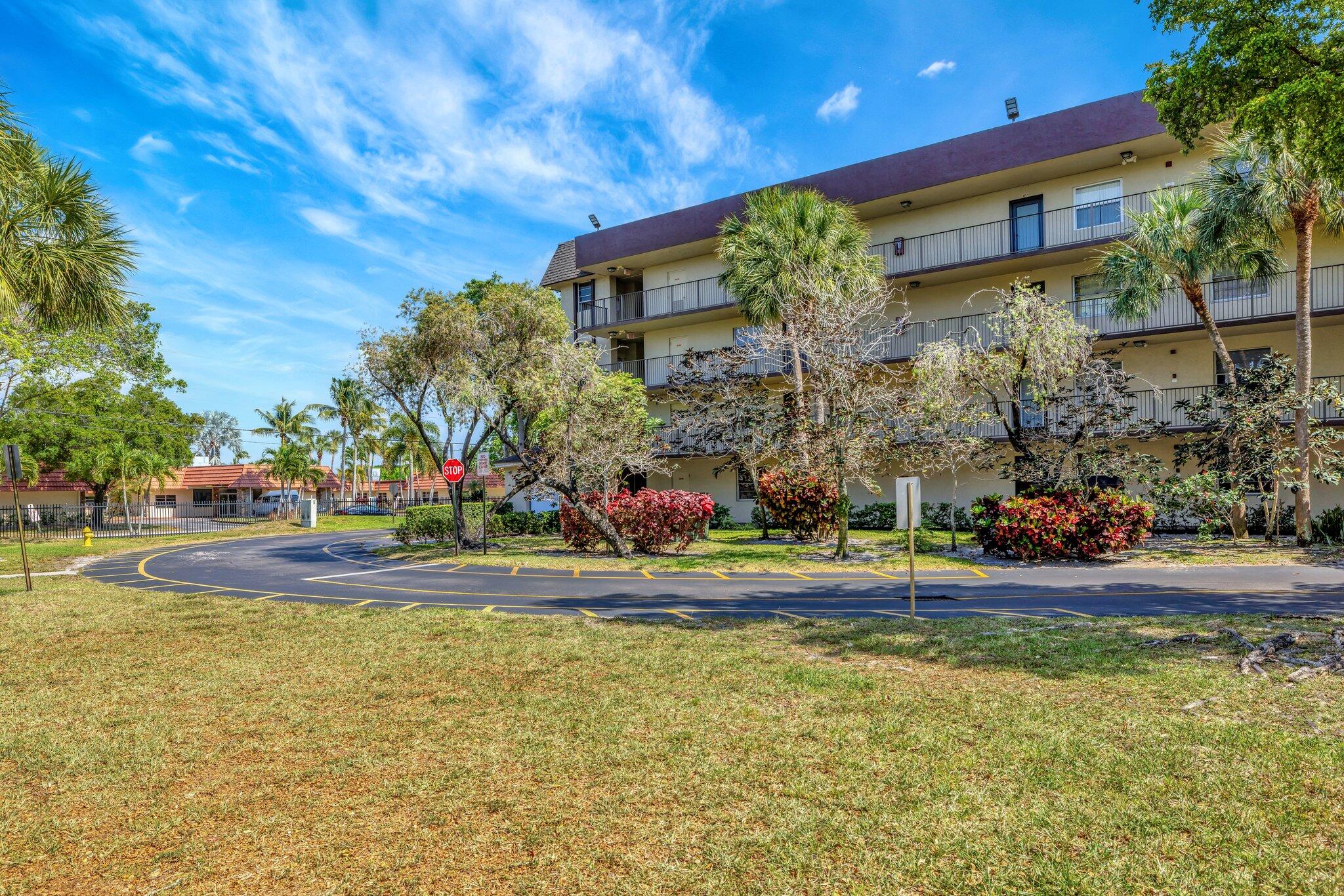 3301 Northwest 47th Terrace, Unit 410 Lauderdale Lakes, FL 33319 - Photo 30 of 58 a front view of a house with a yard and large trees