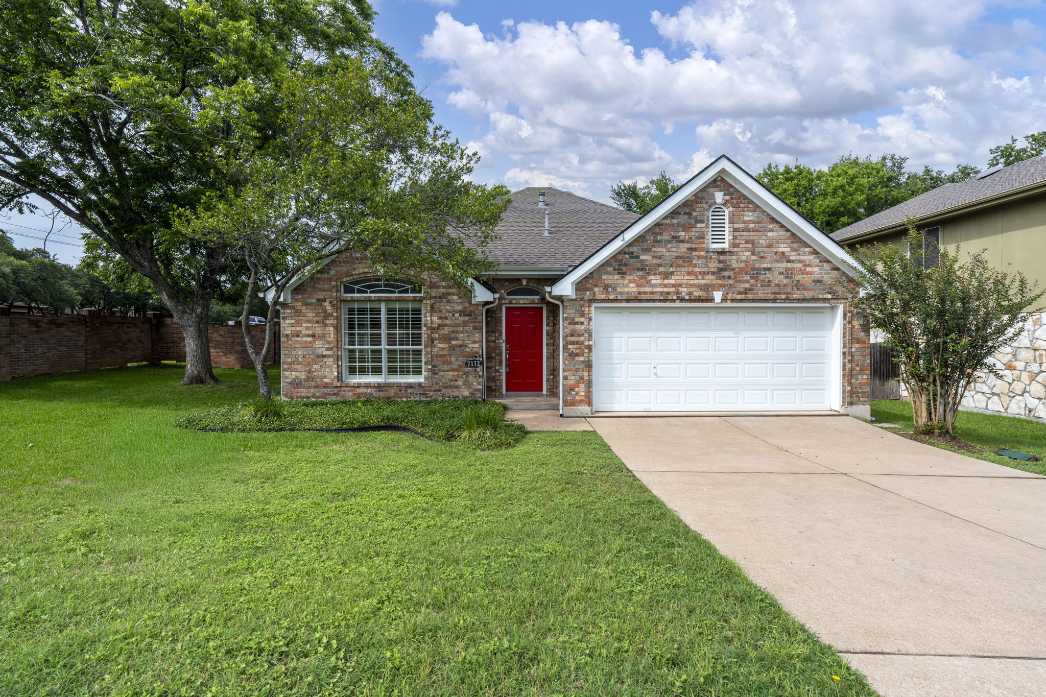 A classic brick exterior with an inviting red entry door and a well-maintained lawn.
