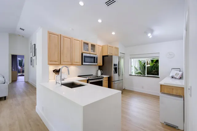 a large white kitchen with sink a microwave and cabinets