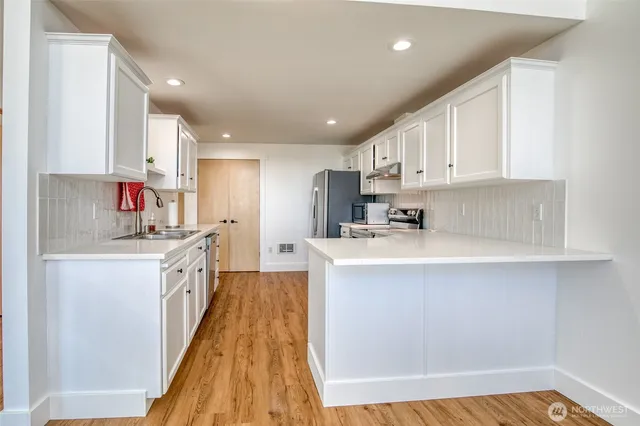 a kitchen with cabinets wooden floor and stainless steel appliances
