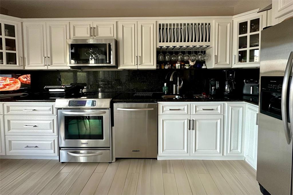 7582 Regency Lake Drive, Unit 301 Boca Raton, FL 33433 - Photo 17 of 20 a kitchen with stainless steel appliances a stove a microwave and cabinets