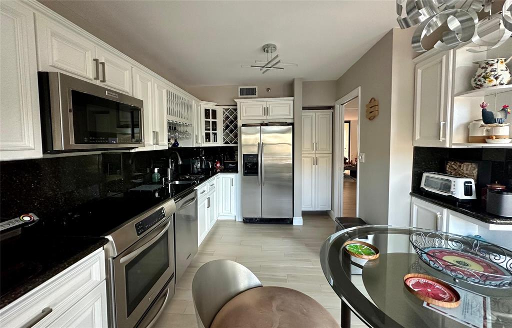 7582 Regency Lake Drive, Unit 301 Boca Raton, FL 33433 - Photo 18 of 20 a kitchen with stainless steel appliances granite countertop a refrigerator a stove top oven a sink and dishwasher