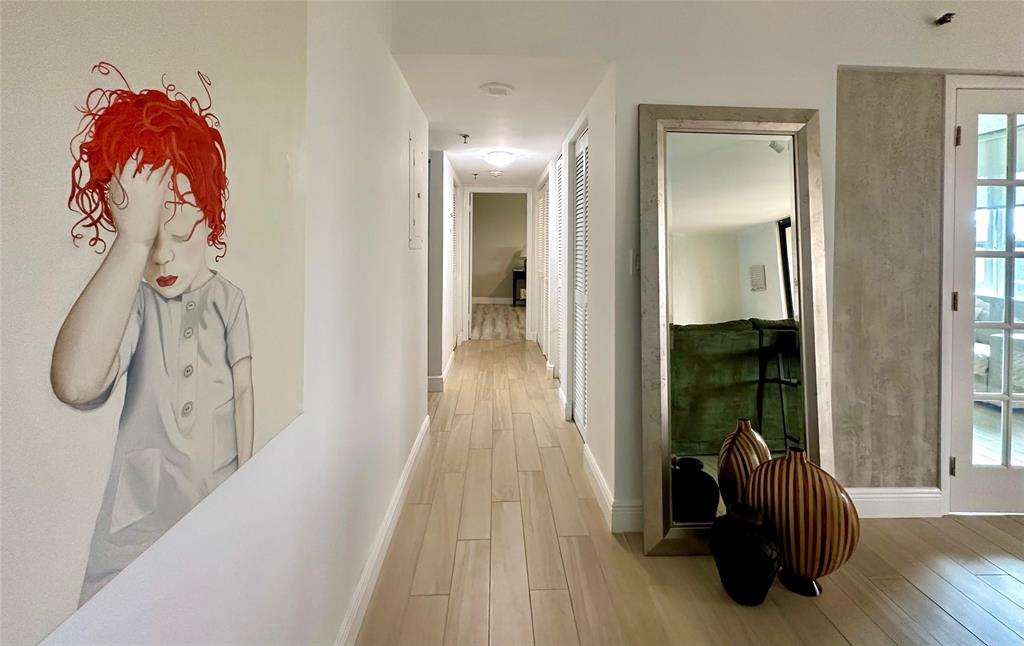 7582 Regency Lake Drive, Unit 301 Boca Raton, FL 33433 - Photo 6 of 20 a hallway with two couches and a large mirror with wooden floor