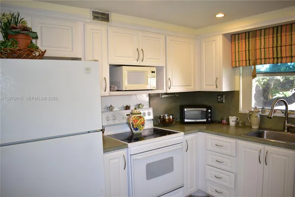 a kitchen with white cabinets and white appliances