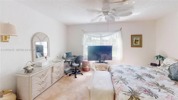 a bedroom with bed a flat tv screen and a dresser