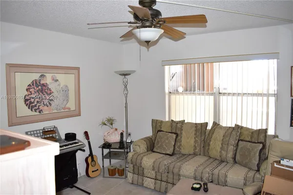 a living room with furniture a chandelier fan and a window