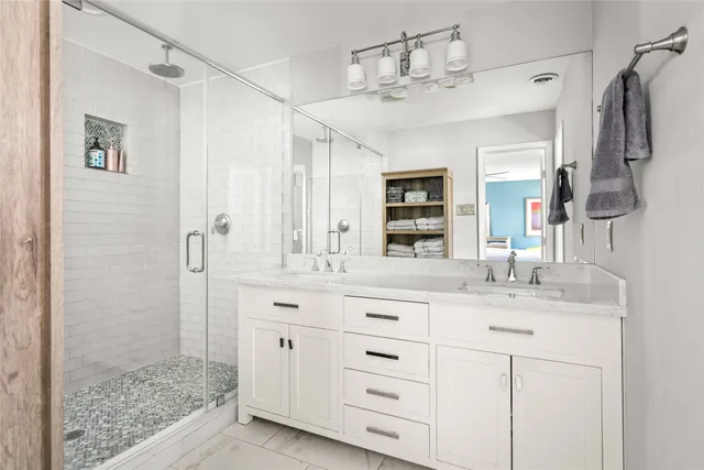 a bathroom with a double vanity sink mirror and shower