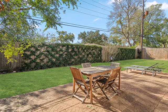 a patio with table and chairs and potted plants