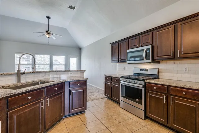 a kitchen with stainless steel appliances granite countertop a stove sink and microwave