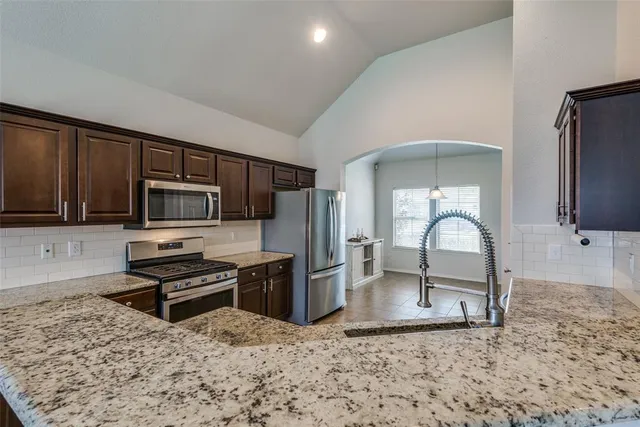a kitchen with stainless steel appliances granite countertop a stove a refrigerator and a sink