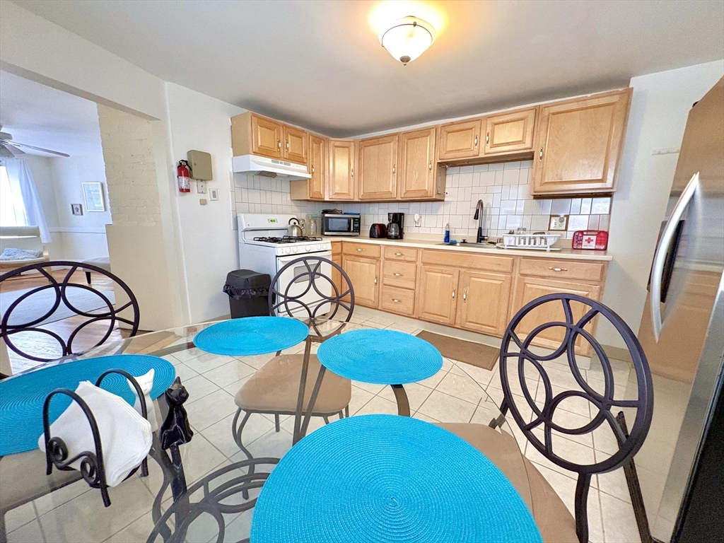 285 Roxbury Street Boston, MA 02119 - Photo 4 of 15 a kitchen with stainless steel appliances granite countertop a dining table chairs and a refrigerator
