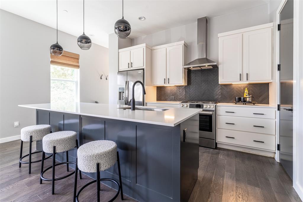 4620 Munger Avenue, Unit 107 Dallas, TX 75204 - Photo 4 of 28 a kitchen with stainless steel appliances a sink a stove a refrigerator and white cabinets with wooden floor