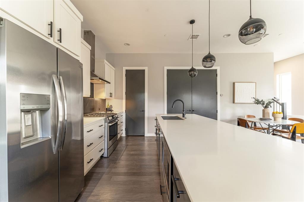 4620 Munger Avenue, Unit 107 Dallas, TX 75204 - Photo 6 of 28 a kitchen with stainless steel appliances a stove a refrigerator a sink and dishwasher with wooden floor