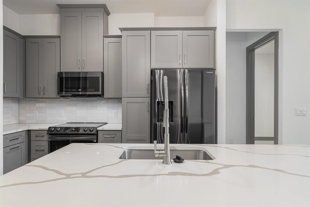 2700 Old Denton Road, Unit 3336 Carrollton, TX 75007 - Photo 11 of 29 a kitchen with stainless steel appliances kitchen island granite countertop a refrigerator and a stove top oven
