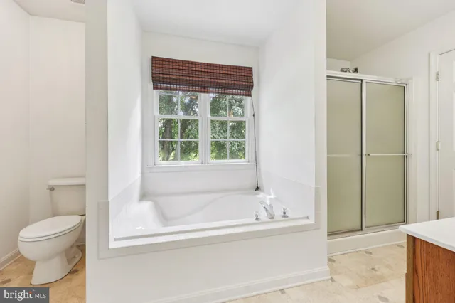 a bedroom with a large bed a potted plant and a window